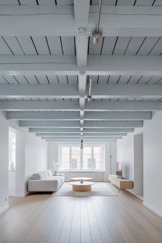 Exposed ceiling joists painted flat matte white with matching ceiling void in a bright modern Scandinavian living room